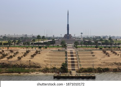 Ismalia, Egypt - 11 05 15: Large Egyptian War Memorial On The Banks Of The Suez Canal In A Desert Landscape With Palm Trees 