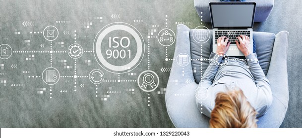 ISO 9001 With Man Using A Laptop In A Modern Gray Chair