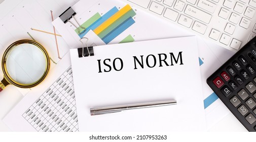 ISO NORM text on the white paper on light background with charts paper ,keyboard and calculator