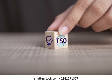 ISO quality control certification concept. Hand flip ISO smart globe icons with check mark guarantee icon on wooden cube and copy space.