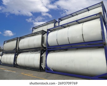 Iso tank container stack at a logistics terminal, featuring multiple cylindrical tanks used for bulk liquid storage and international shipping. Ideal for illustrating themes of global supply chain