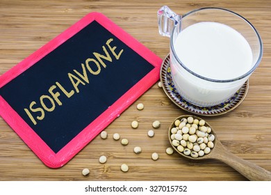 Isoflavone written on chalkboard with a cup of soy milk and soybeans on wood background