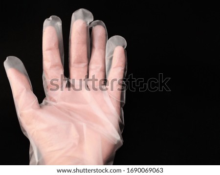 An isolate image of a hand wearing plastic gloves on a black background.  Used in the prevention of coronary viruses.
