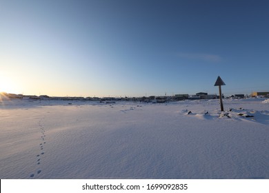 Isolated Arctic Landscape With Inuit Community In The Background And Single Set Of Footsteps In The Snow, Rankin Inlet, Nunavut Canada