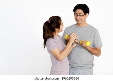 Isolated Asian Middle Aged Happy Healthy Senior Retirement Elderly Grandparent Couple Wears Sport Cloth Stand Workout With Dumbbells And Squeeze Hand Coil Exercise Together In Front White Background.