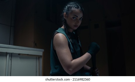 Isolated Bad Ass Woman Kickboxer Looking Directly at the Camera As She Wraps Her Hands Before Heading Off to Train in a Boxing Ring With Her Coach. Confident Female Boxer Resting After Training. - Powered by Shutterstock