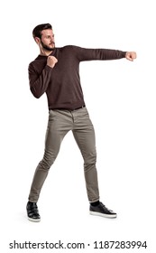 An isolated bearded man in casual clothes punches empty air on a white background. Strength and training. Boxing and sport. Hitting opponents. - Shutterstock ID 1187283994