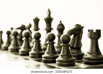 Isolated black chess figures on the chessboard toned with dark gold color. Conceptual chess and leisure activity backgrounds