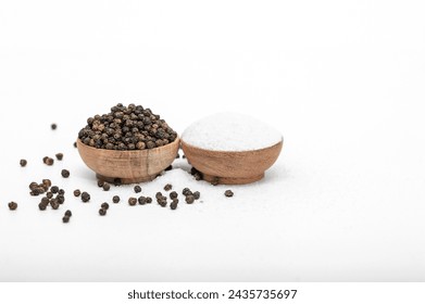 Isolated black peppercorns next to fine grain table salt - Powered by Shutterstock