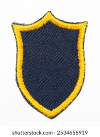 Isolated blank black shield patch with gold embroidered outline.