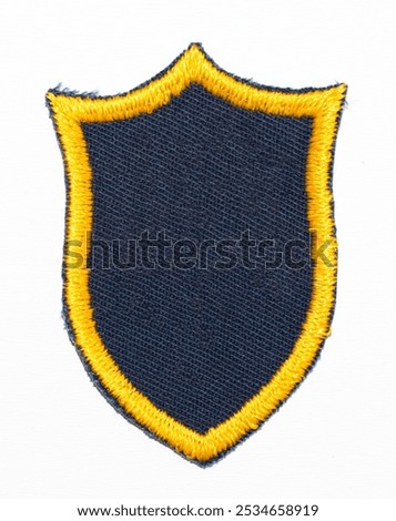 Isolated blank black shield patch with gold embroidered outline.