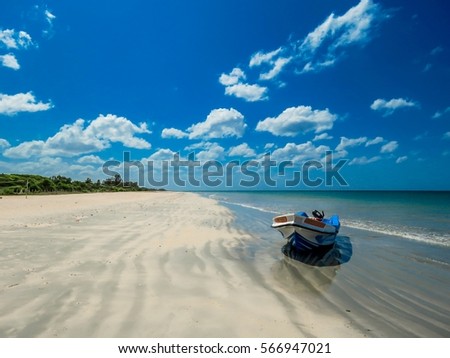 Isolated Boat on Amazing Beautiful scenic unspoiled white sand sandy beach with sand pattern and blue sky with white clouds near Pigeon Island in Trincomalee, Sri Lanka