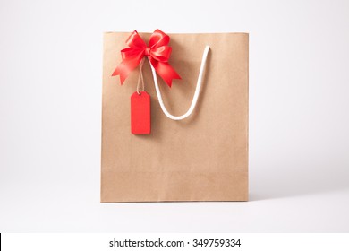 Isolated brown paper shopping bag and blank tag, label with red bow on white background - Powered by Shutterstock