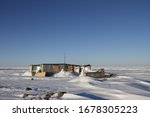 Isolated cabin with komatik (Inuit sled) in front and snow on the ground in an arctic landscape, near Arviat, Nunavut Canada