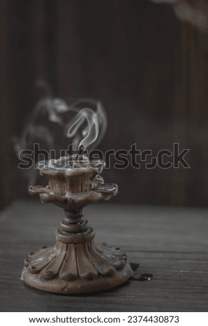 Isolated candle on black with vintage retro candle holder emitting a smoke