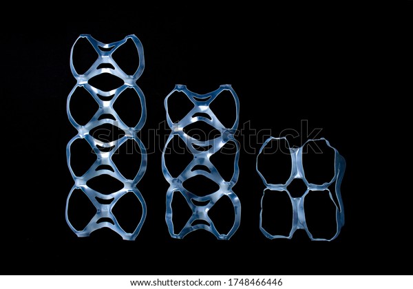 Isolated cans pack rings or four, six, eight,\
pack yokes, connected plastic rings used in multi-packs of beverage\
on a black background
