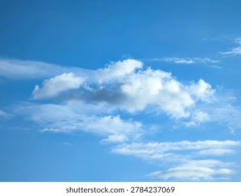 Isolated cascading cloud floating in the wind against blue cirrus sky. Big glowing clouds spreading on the deep blue sky sunny day. Nature concept background. Elegant landscape soft image