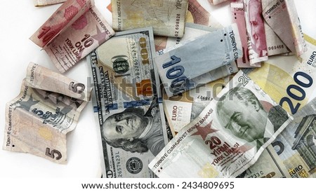 Isolated cash on a white background. Assorted Turkish lira bills with US dollars and euros, all on a well-lit surface.



