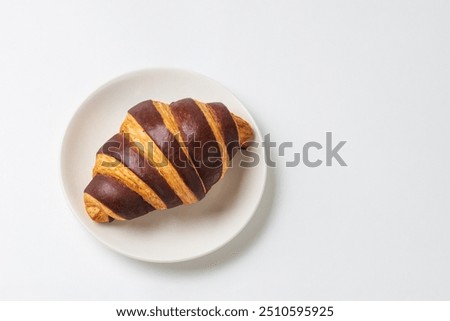 Isolated chocolate croissant on white plate on white background top view with copy space