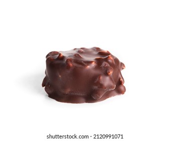 Isolated chocolate praline with hazelnut pieces. Closeup of one small non uniform chocolate truffle piece coated with dark chocolate. Selective focus.