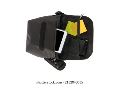 Isolated Close Up Studio Shot Of Small Black Messenger Crossbody Shoulder Long Strap Sling Bag Contains Colorful Post It Wallet And Touchscreen Tablet Computer Inside In Front Of White Background.