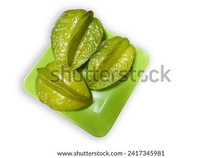 isolated close up top shot of three green star fruits (also known as Carambolas) on a green plate