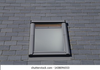 An Isolated Close Up View Of A Flat  Window Inserted In A Slate Tiled Roof.