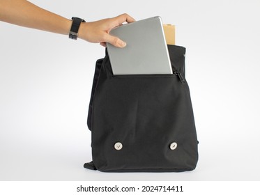 Isolated Closeup Studio Shot Of Woman Hand Pick Up Tablet Computer From Compartment Pocket Of Black Messenger Bag On White Background.