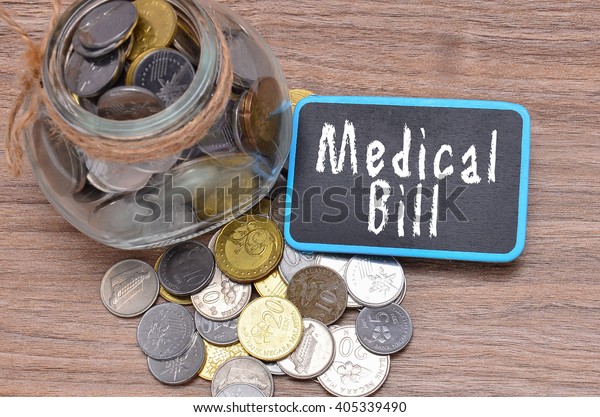 Isolated coins in jar with Medical Bill word on\
mini chalkboard - financial\
concept