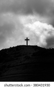 Isolated cross on hilltop above Hana in Maui, Hawaii with dramatic cloud cover. Black and white.
