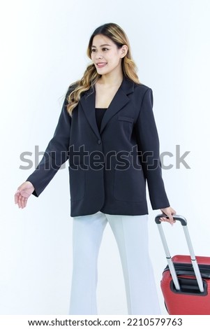 Isolated cutout studio full body shot of Millennial Asian successful professional female businesswoman in formal suit walking holding pulling trolley luggage for business trip on white background.