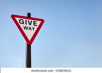 Isolated English give way street sign again blue sky background. Space for copy text