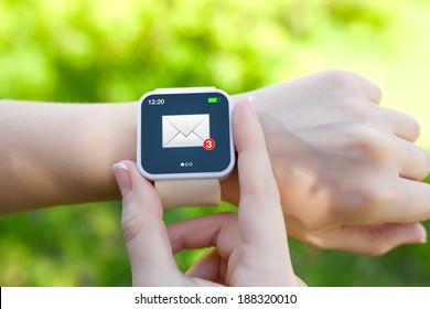 Isolated female hands with white smartwatch with email on the screen on a background of green grass - Powered by Shutterstock