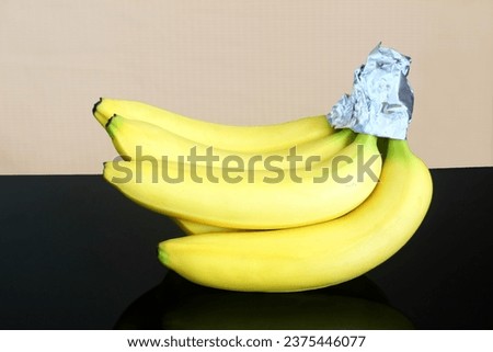 isolated fresh organic ripe yellow banana fruit protection or preservation from turning brown and keep fresh longer with aluminium foil cap wrap   