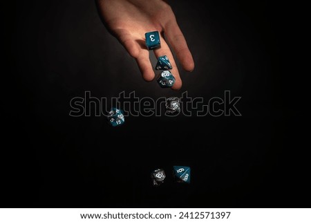 isolated hand dropping polyhedral dice in front of a black background