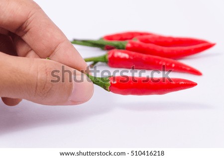 Isolated of hand picking up a fresh red chilli and many chilli in white background