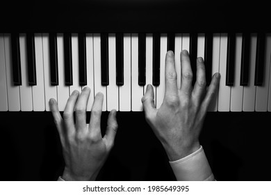 Isolated hands playing on the piano, dark background, black and white photo