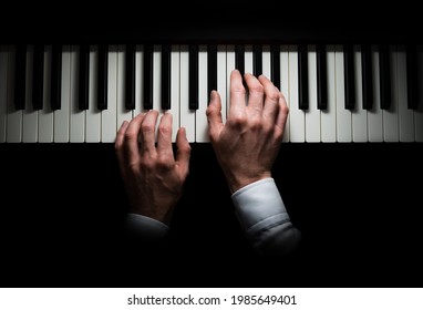 Manos aisladas tocando el piano, fondo oscuro
