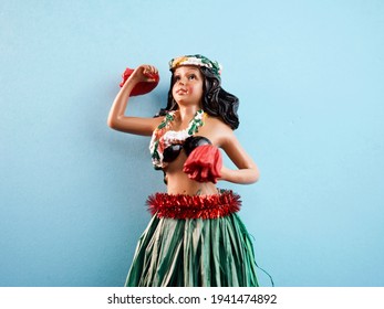 Isolated Hawaiian Hula Girl Doll In Center Of Frame Against Light Blue Background