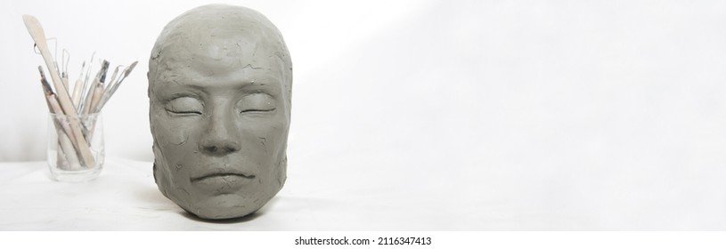 Isolated head sculpture and handmade art tools on white background. Portrait of a female mask for art instruction and workshops. - Shutterstock ID 2116347413