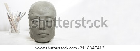 Isolated head sculpture and handmade art tools on white background. Portrait of a female mask for art instruction and workshops.