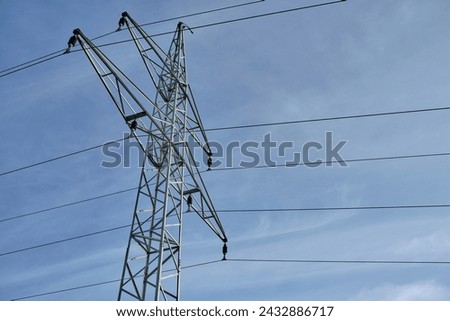 Isolated high-voltage transmission tower supporting power lines against blue sky on a sunny day. Negative space. Building, maintaining above-ground electric grid simple concept. Czech Republic, Europe