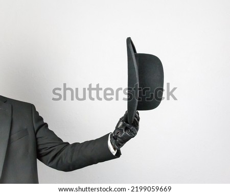 Isolated Image of Gentleman in Dark Suit and Leather Gloves Politely Doffing Bowler Hat. Classic British Butler or British Businessman.