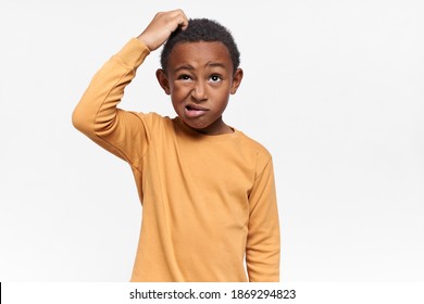 Isolated image of perplexed frustrated African American schoolboy grimacing and looking up, scratching his head, having confused facial expression, forgot something important. Body language - Powered by Shutterstock