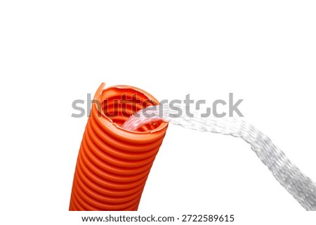 Isolated innerduct conduit with pull string, close up. Conduit system for cable management or cable pulling for fiber optics or high-speed internet upgrades. Orange pipe with string. Selective focus.