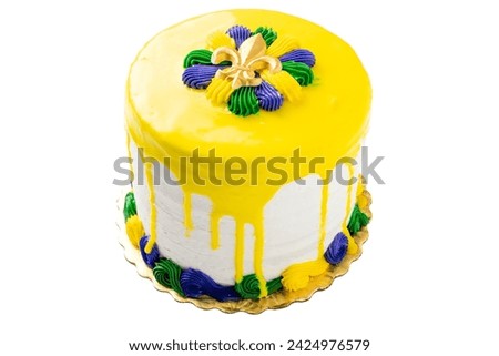 Isolated Mardi Gras vanilla cake with yellow icing pour has a gold fleur de lis on top of yellow, green and purple icing pattern. Quarter angle.