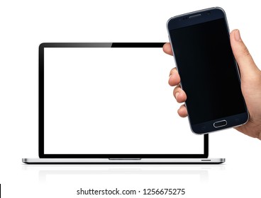 Isolated Mockup Of Mobile Phone And Computer. Hand Holding A Samsung Cellphone In Front Of A Macbook.   