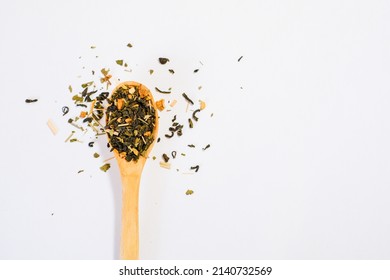 Isolated natural elite high-quality green tea with pieces of fruit, flower petals in wooden spoon. Tea ceremony, premium organic eco sort of tea. Minimalistic simple natural light flat lay template. 