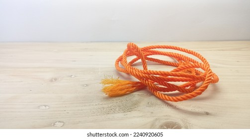 Isolated Object: orange rope medium size, on a wooden background