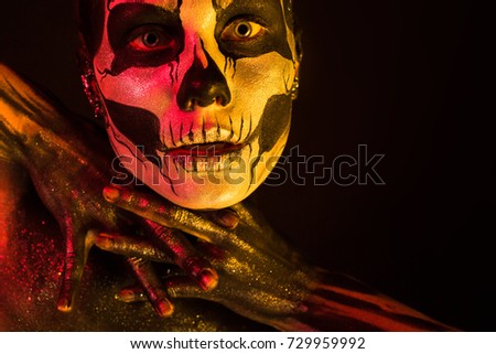 Isolated on black, closeup picture, toned red and yellow, beautiful young blonde caucasian woman with scull body art, grey eyes, crossed fingers
